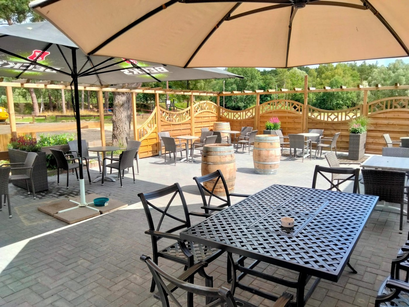 Terrasse mit Sonnenschirmen – Gastronomie im Hoope Park Wulsbüttel Überdachte Terrasse mit Sonnenschirmen, Korbmöbeln und Fassstehtischen in der Gastronomie im Hoope Park Wulsbüttel